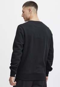Svart crewneck sweatshirt gjord av mjuk bomullsblandning. Har ribbad mudd och nederkant. Enkel design med en slät textur och minimalistiska detaljer.