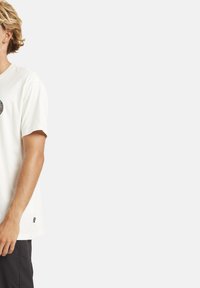 Weißes Baumwoll-T-Shirt mit kurzen Ärmeln, versehen mit einem kreisförmigen Grafikdesign auf der Vorderseite und einem Logoetikett am seitlichen Saum.