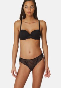 Sostenedor negro de encaje con varilla y tirantes ajustables; bragas de encaje negro transparente a juego con patrones florales y bordes festoneados.