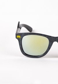 Black plastic sunglasses with green-tinted lenses, featuring a yellow Batman logo on the frame, and a rectangular shape.