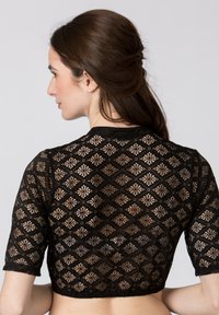 Schwarzes, kurzes Oberteil mit kompliziertem diamantförmigem Spitzenmuster, kurzen Ärmeln und einem gewellten Saum, der eine transparente Textur zeigt.