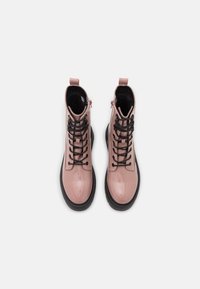 Bottes de cheville en cuir verni rose avec des lacets noirs, une fermeture éclair sur le côté, une doublure intérieure texturée et une semelle en caoutchouc noire.