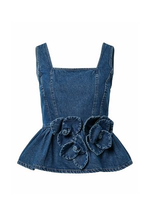 Kvinne iført mørkeblå denim ermeløs topp med 3D-blomsterdetaljer og matchende vide jeans, stående foran en ensfarget lys bakgrunn.