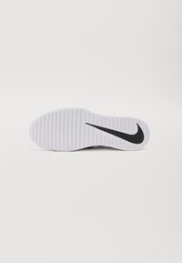 Bílá podrážka boty s texturovaným gripem a velkým černým logem Nike swoosh umístěným na pravé straně.