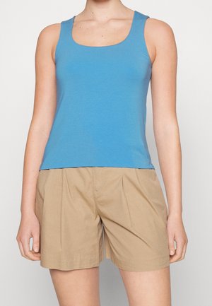 Blue cotton tank top with a square neckline and wide straps, paired with beige shorts featuring a pleated design and side pockets.