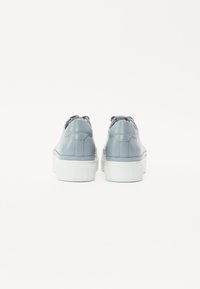Blå lærersneakers med en hvid gummisål, der har en polstret krave og teksturerede accenter bagpå. Minimalistisk design.