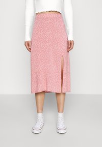 Rosa blommig midiklänning med en sidosprund. Gjord av lätt material, har ett subtilt vitt blommönster. Tillsammans med vita sneakers.