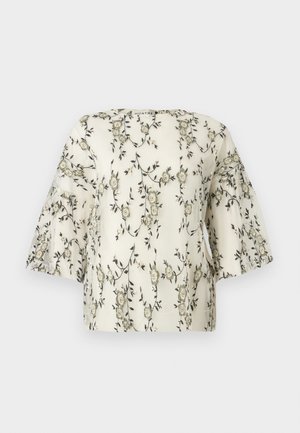 Haut brodé de fleurs en crème, avec des manches courtes et larges et une surface texturée ornée de motifs floraux vert foncé et beige.