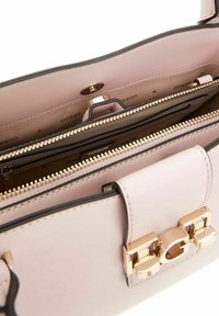 Sac à main en cuir rose clair avec quincaillerie dorée, compartiments zippés et coutures détaillées. L'intérieur présente plusieurs poches et un imprimé de logo.