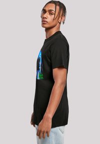 Black cotton t-shirt featuring a vibrant graphic print of a face with blue and green accents. Classic fit with short sleeves.