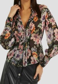 Bluse mit floralem Muster und langen, aufgebauschten Ärmeln, mit schwarzem Hintergrund, verschiedenen bunten Blumen und plissiertem Detail am Ausschnitt.