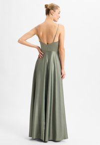 Langes, fließendes satinartiges Kleid in Olivgrün mit tiefem Rückenausschnitt, dünnen Trägern und einem Reißverschluss. Es zeichnet sich durch eine glatte Textur und einen eleganten Fall aus.