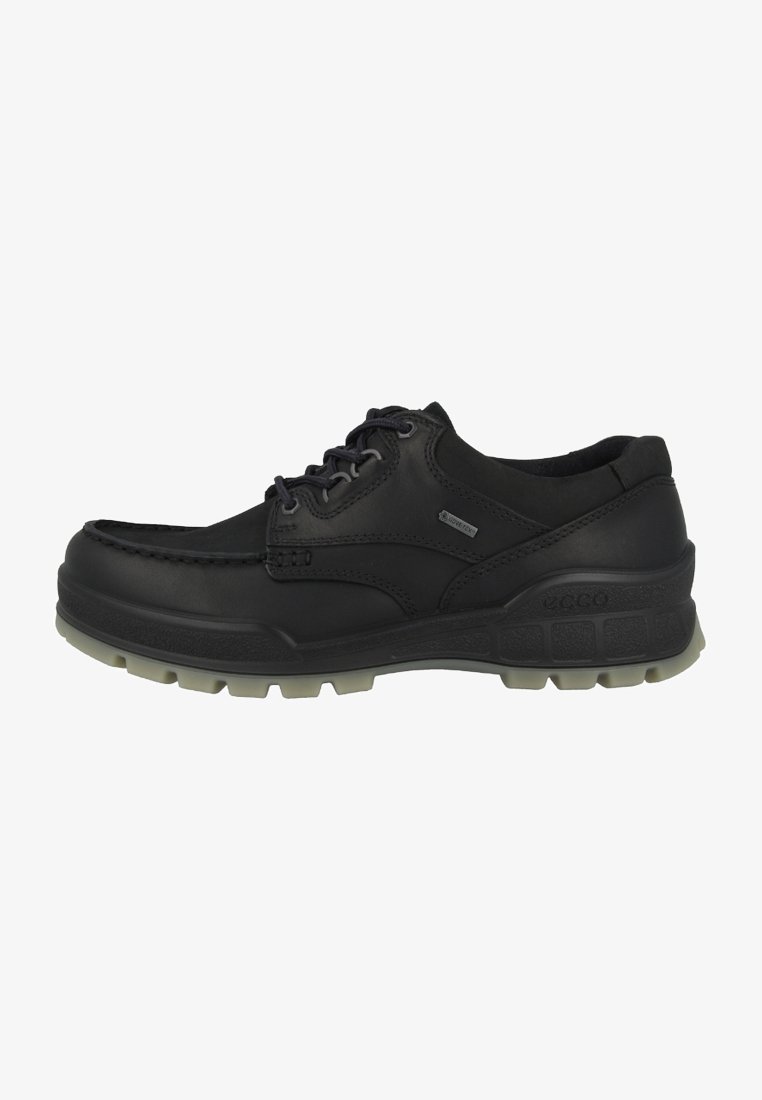 Chaussure noire basse à lacets avec semelle robuste, coutures moc toe, et une petite étiquette « GORE-TEX » sur le côté indiquant l'imperméabilité.