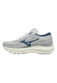 Scarpa sportiva con parte superiore in maglia grigia chiara, dettagli blu navy, lacci bianchi e una suola bianca ammortizzata con motivi ondulati per una maggiore flessibilità.