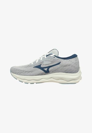 Scarpa sportiva con parte superiore in maglia grigia chiara, dettagli blu navy, lacci bianchi e una suola bianca ammortizzata con motivi ondulati per una maggiore flessibilità.