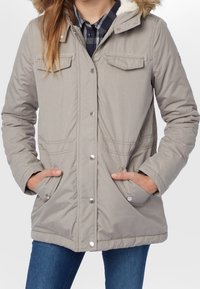 Světle šedá parka s kapucí a umělou kožešinou, která má patentky, dvě náprsní kapsy a boční kapsy. Měkká, zateplená tkanina, volný střih.