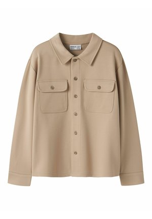 Chemise beige à manches longues avec boutons, deux poches à rabat devant et un col pointu, réalisée en tissu texturé.