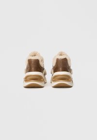 Adidași din piele maro cu accente pufoase de culoare bej și tălpi transparente cu amortizare. Formă rotundă cu un finisaj din piele texturată.