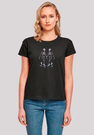 Black cotton t-shirt featuring a graphic of two skeletons on ice skates. Short sleeves, round neck, relaxed fit, soft texture.