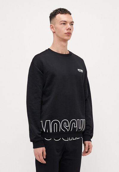 Black sweatshirt with ribbed crew neckline, textured fabric, elastic cuffs, and bold white "MOSCHINO" branding at the bottom.
