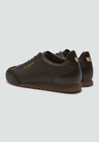Zapatillas de cuero marrón con un acabado suave, que presentan detalles cosidos, suela de goma marrón y el logo dorado "PATRICK" en el lateral.