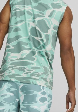 Top senza maniche in teal e verde con motivi astratti e ondulati; realizzato in materiale morbido. Presenta una vestibilità comoda e un orlo curvo.