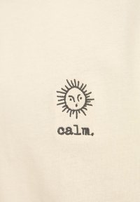 Cremefarvet bomulds t-shirt med et sort broderet solgrafik og ordet "calm." under. Blød tekstur med en afslappet pasform.
