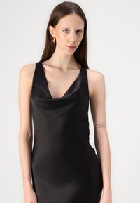 Black satin dress with a cowl neckline and sleeveless design. Smooth texture and form-fitting shape, featuring a subtle sheen.