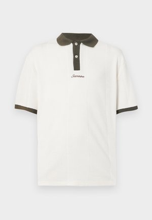 Bela polo majica s temno zelenim ovratnikom. Ima pleteno teksturo in trojni gumbni zapenjalni del. "Samsoe" logotip v rjavi barvi vezen na sprednji strani.