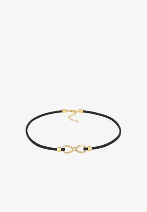 Czarny zamszowy naszyjnik choker z detalem w postaci złotego symbolu nieskończoności, z małym przejrzystym kamieniem. Regulowane zapięcie łańcuszka z tyłu.