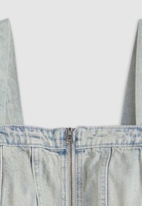 Top in denim azzurro chiaro con spalline larghe, presenta una cerniera centrale e una texture arricciata attorno alla vita. Cuciture dettagliate in tutto il capo.