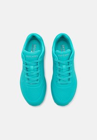 Turkise treningssko med mesh-overdel, perforert design, snøring og polstret krage, som har "SKECHERS"-merke.