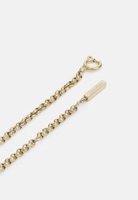 Collana in oro con un design texturizzato e intrecciato, dotata di una chiusura a gancio e di un tag rettangolare inciso con "Calvin Klein."