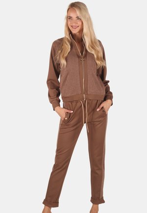 Brown zip-up jacket with ribbed front, paired with matching drawstring pants featuring side pockets and tapered cuffs. Smooth texture.