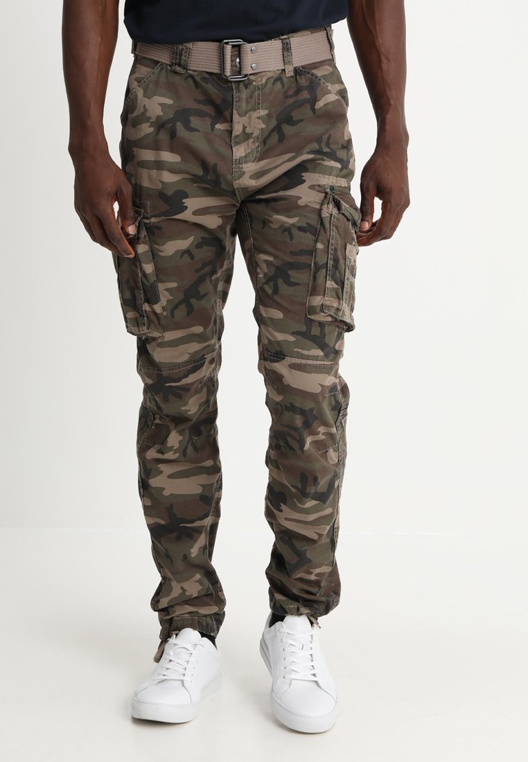Camo cargo pants in groen- en bruintinten, met zijzakken en een taps toelopende pijp met een elastische manchette, gecombineerd met witte sneakers.