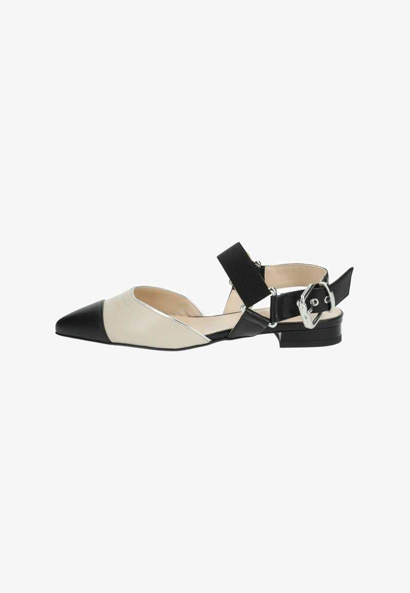 Shoe plateaux à bout pointu en cuir beige avec un accent noir au niveau de la pointe. Présente une bride noire avec des accessoires en argent et un talon bas.