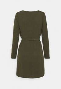 Olivgrön, långärmad klänning med rak skärning, ett knytbälte i midjan och dekorativt metalldetaljer vid axelsömmarna.