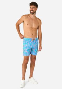 Šviesiai mėlynos maudymosi šortai su ryškiu daugiaspalviu banguotu raštu. Turintys elastinę juosmenį su oranžiniu raišteliu ir šoninėmis kišenėmis.