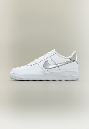 Baskets basses blanches Nike Air Force 1 avec logo Swoosh argent métallique et languette de talon assortie sur fond neutre.