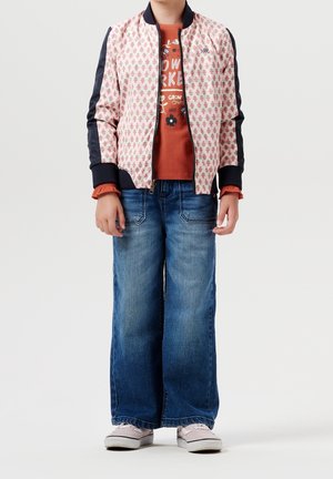 Lyserød bomberjakke med blomstermønster, marineblå ærmer; rustfarvet t-shirt med blomsterprint; brede blå jeans; og lyserøde sneakers.