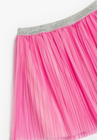 Rosa Plissee-Rock aus durchsichtigem Stoff mit einem glitzernden silbernen Bund. Auffällige vertikale Linien verleihen ein strukturiertes Erscheinungsbild.