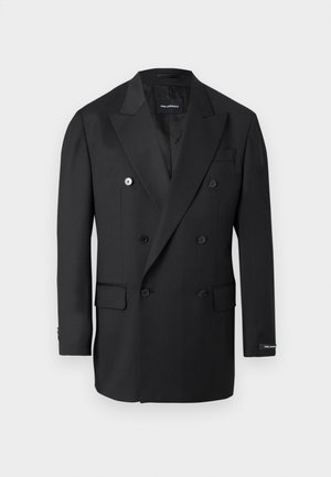 Melns divrindu žakete ar iegriezuma atlokiem, sešām pogām, atloku kabatām un etiķeti uz kreisās piedurknes aproces.