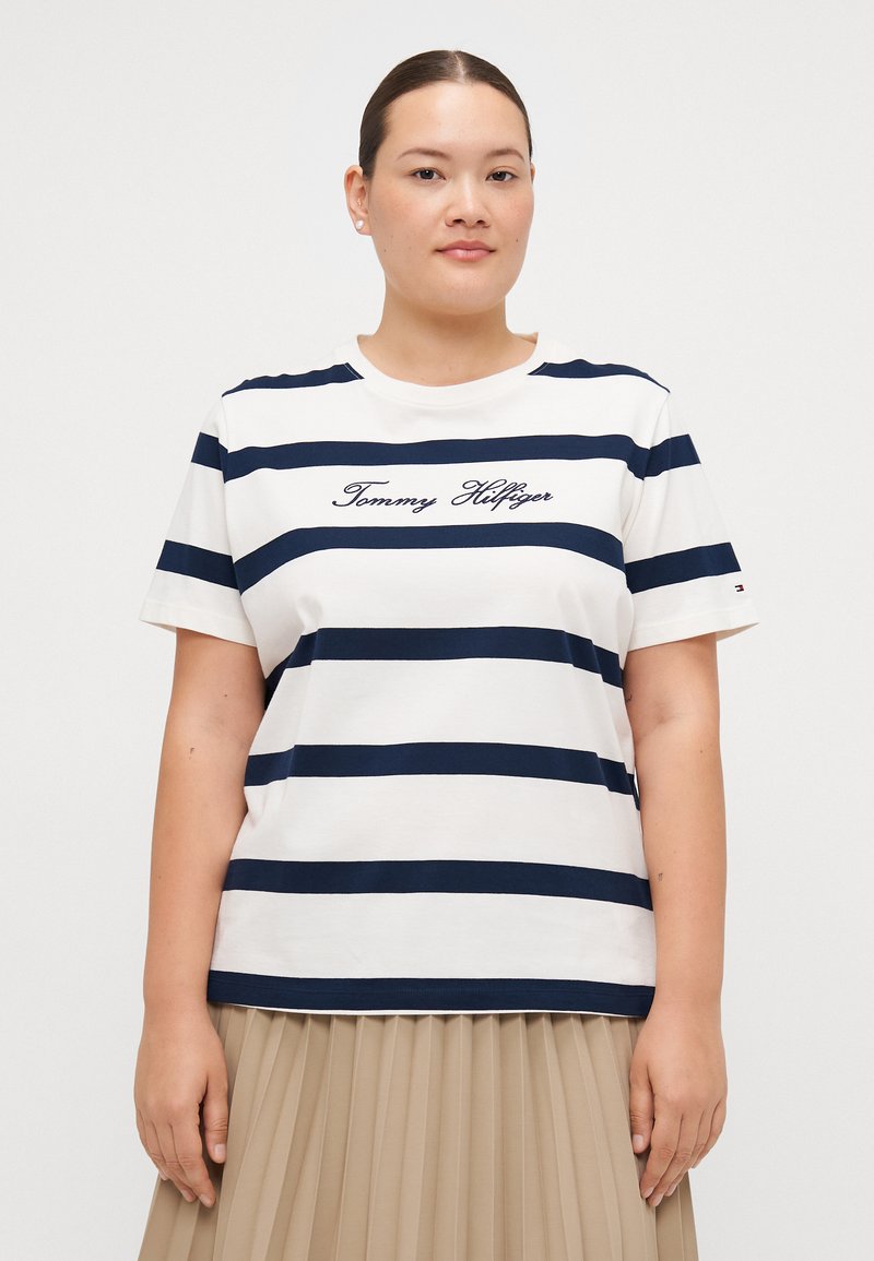 Hvid bomulds T-shirt med marineblå vandrette striber og broderet "Tommy Hilfiger" logo på forsiden. Korte ærmer og rund halsudskæring.