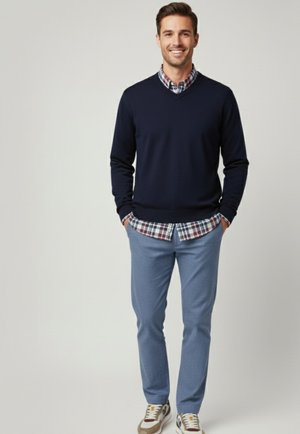 Suéter navy sobre una camisa de cuadros, combinado con pantalones de cuadros azul claro y zapatillas. El conjunto presenta ropa en capas con un ajuste relajado.