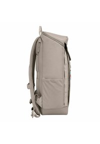 Sac à dos gris rembourré avec poches latérales en maille, bretelles ajustables et une poignée supérieure. Il présente un design élégant et rectangulaire avec des compartiments zippés.
