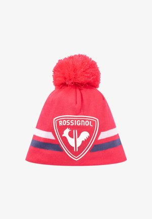Gorro de punto rojo con un gran pompón en la parte superior, que presenta un patrón de rayas en blanco y marino y un logo central de gallo blanco dentro de un escudo.