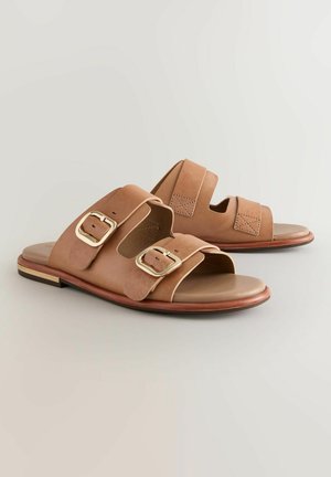 Sandales à glissière en cuir brun avec deux larges brides ornées de boucles en or ; semelle lisse, pointe arrondie et un petit talon en bois.