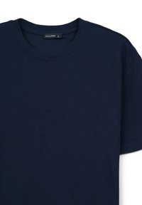 T-shirt blu navy realizzato in tessuto testurizzato, con scollatura classica a girocollo e maniche corte. Etichetta del marchio visibile vicino al collo.