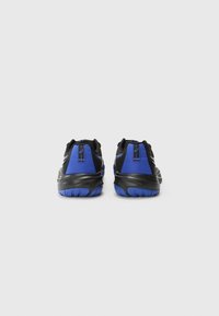 Des chaussures de sport noires et bleues avec une tige texturée, un talon arrondi et une semelle en caoutchouc dotée d'un motif de traction bleu.