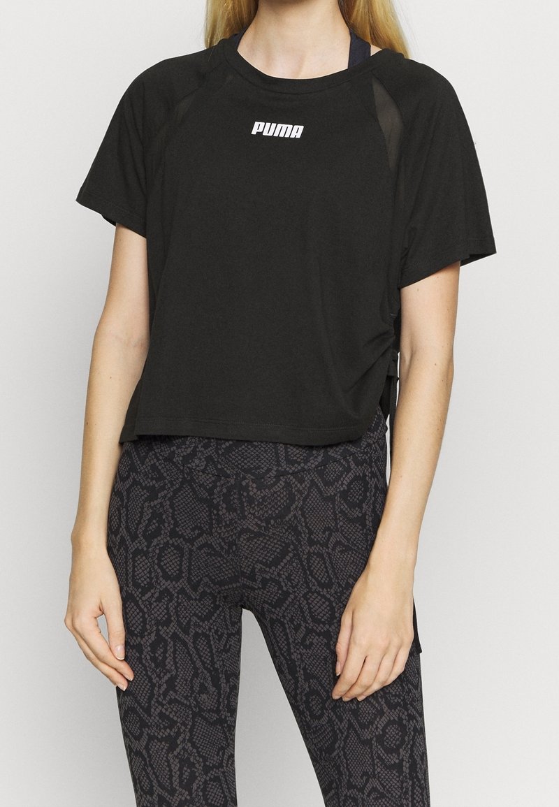 Svart kortärmad t-shirt med en vit Puma-logotyp på bröstet och meshdetaljer på axlarna.